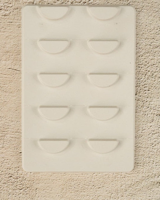 A white, biodegradable lash tray with easy tear segments designed for organizing false eyelashes, yet to be customized.