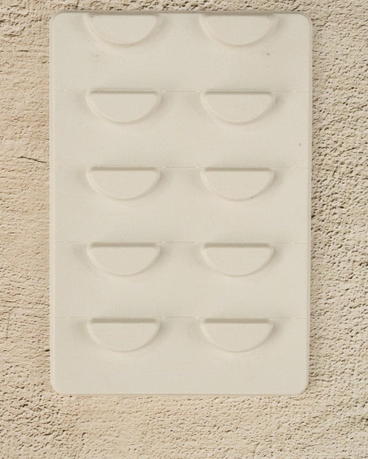 A white, biodegradable lash tray with easy tear segments designed for organizing false eyelashes, yet to be customized.